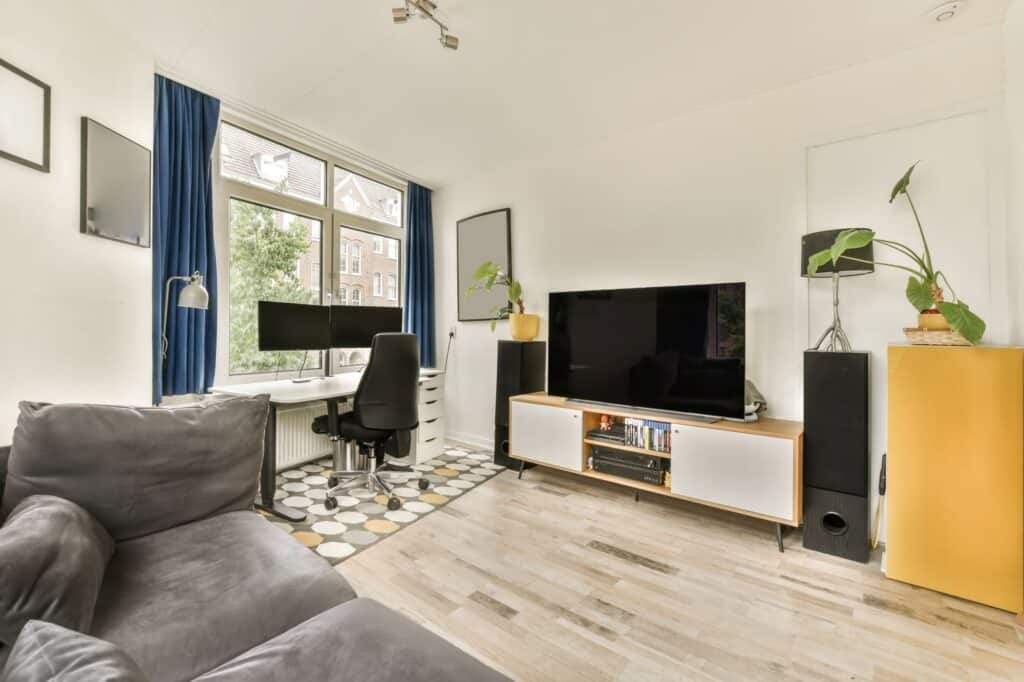 A living room with a flat-screen, couch, and work desk