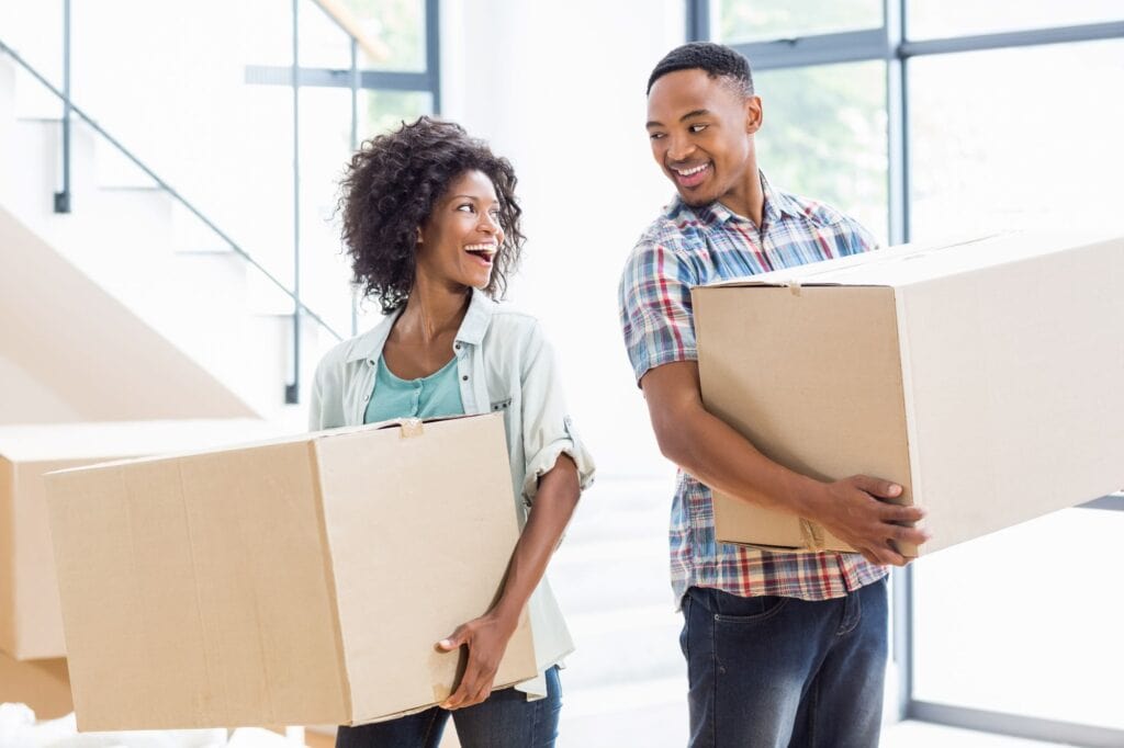 A smiling couple lifting boxes in their new home