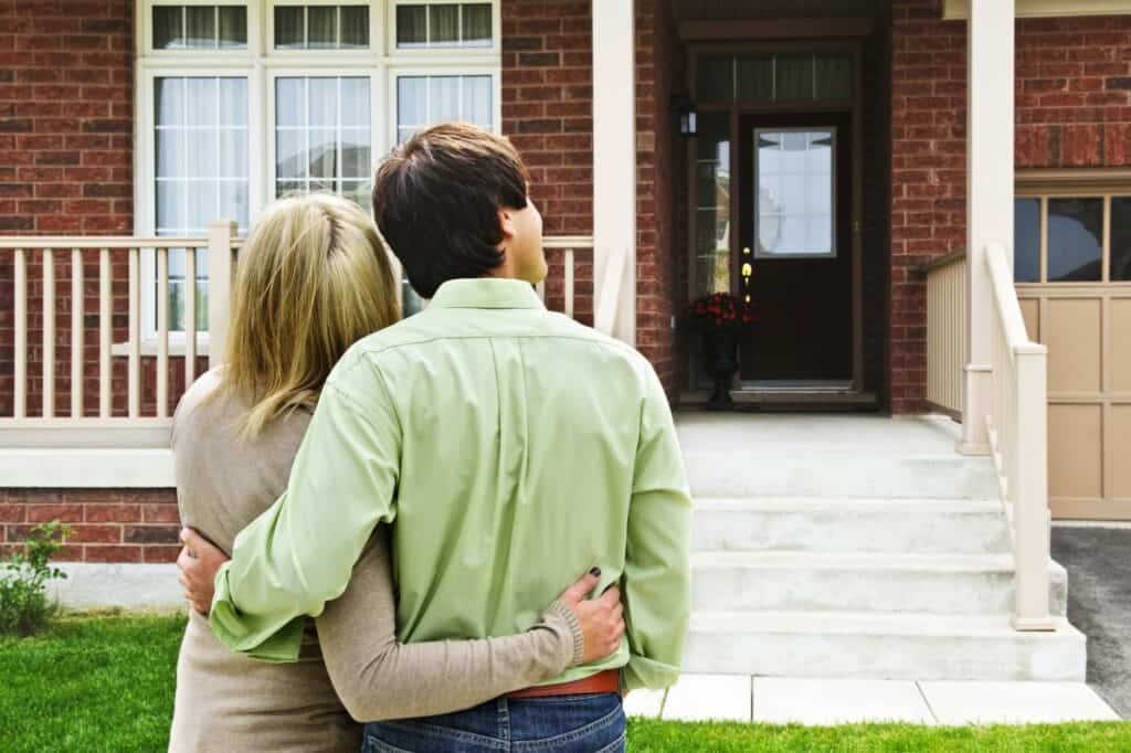 A young couple in front of their new home