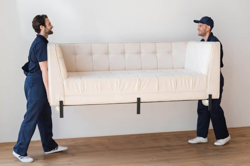 Two workers lifting a sofa during house removal