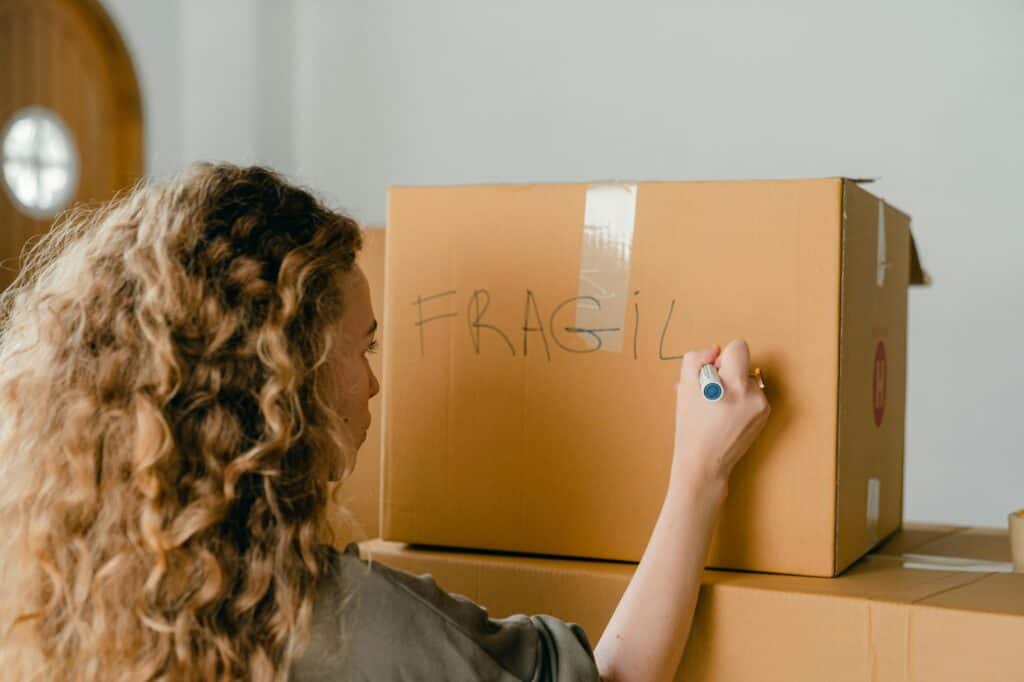 A woman is labelling a box as she is getting ready for the moving day to Enfield.