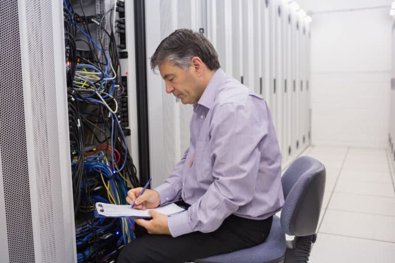 A technician in the server room taking notes