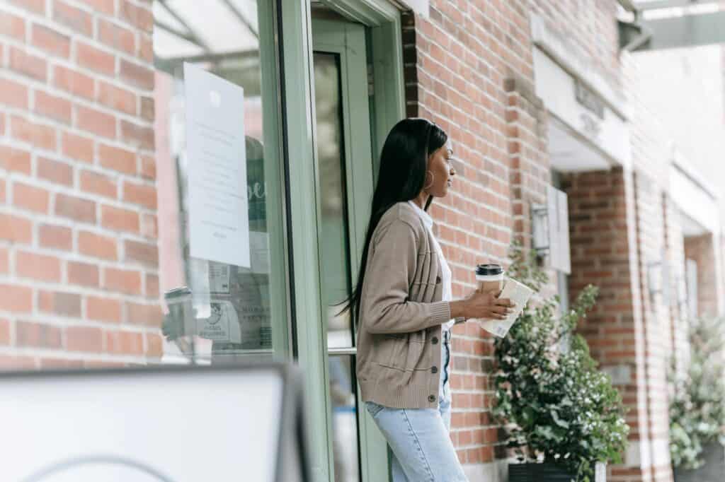 A woman is walking out of a coffee shop