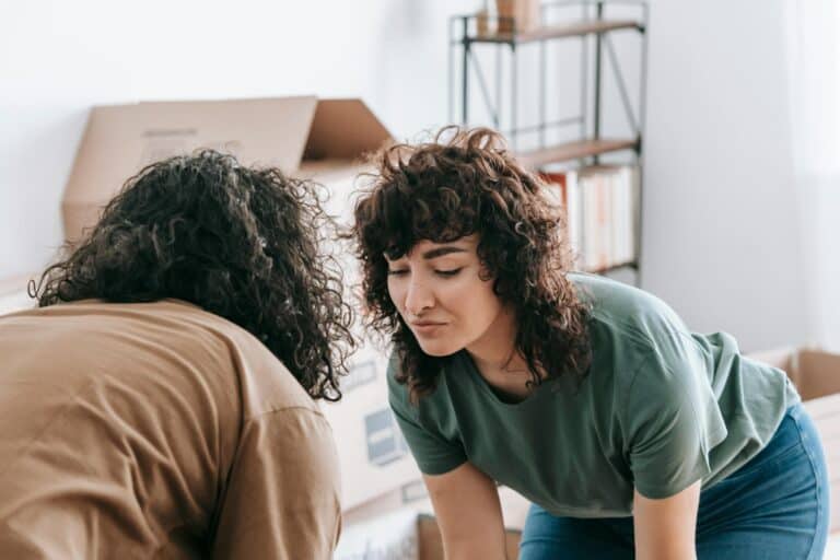 A couple placing a table in the living room in the concept of 'best affordable housing options when moving to Enfield'.